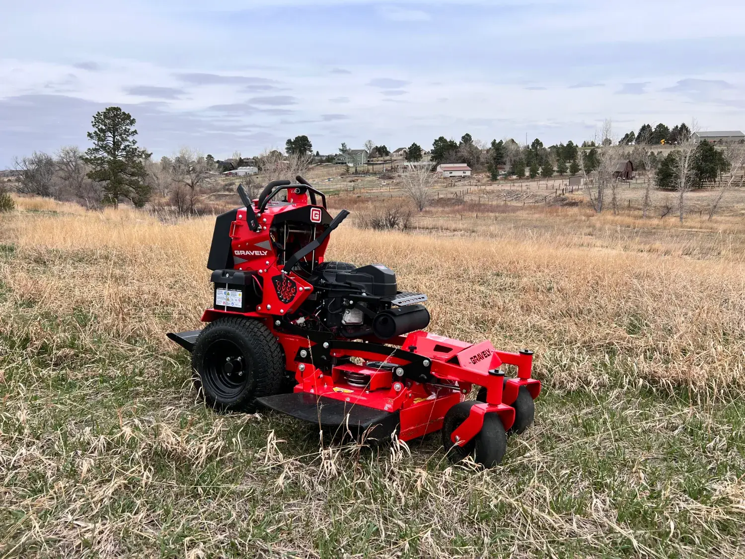 Stand-on mower in tall grass on open acreage